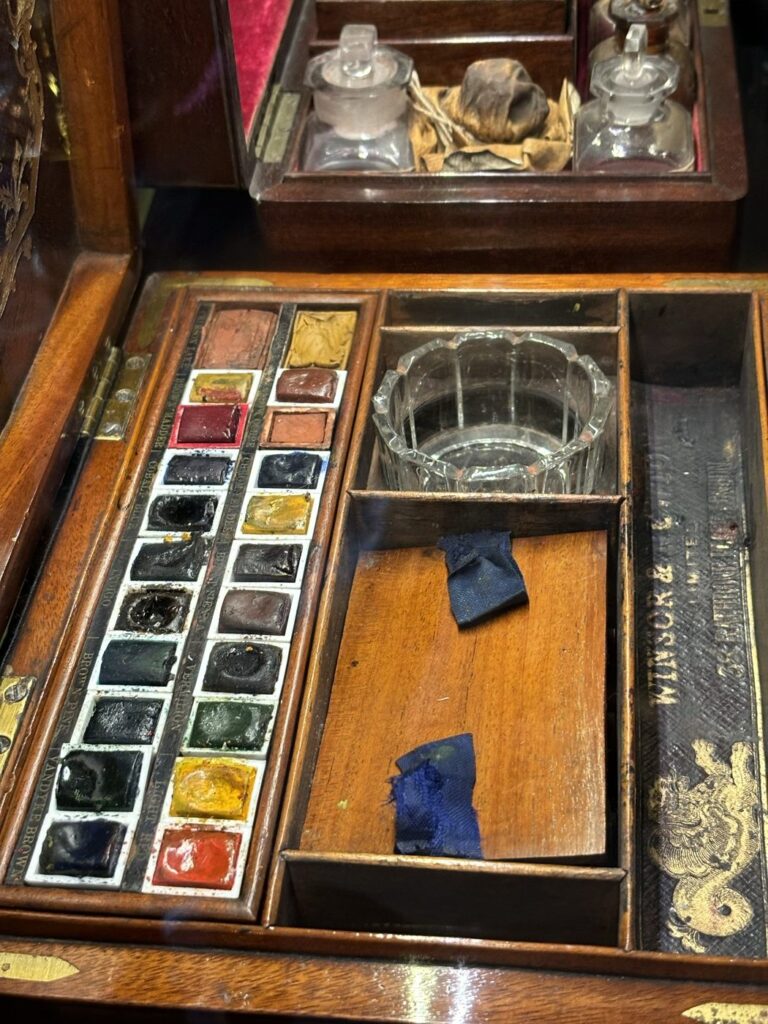 BAM鎌倉に展示されたウィンザー＆ニュートンのアンティーク水彩絵の具箱。マホガニーの箱に使いかけの固形絵具が並び、ガラスの水入れが収まっている