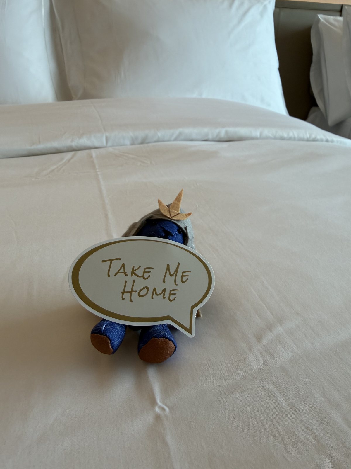 コンラッド名古屋の客室ベッドに置かれた武将姿のコンラッドベアと「TAKE ME HOME」のカード