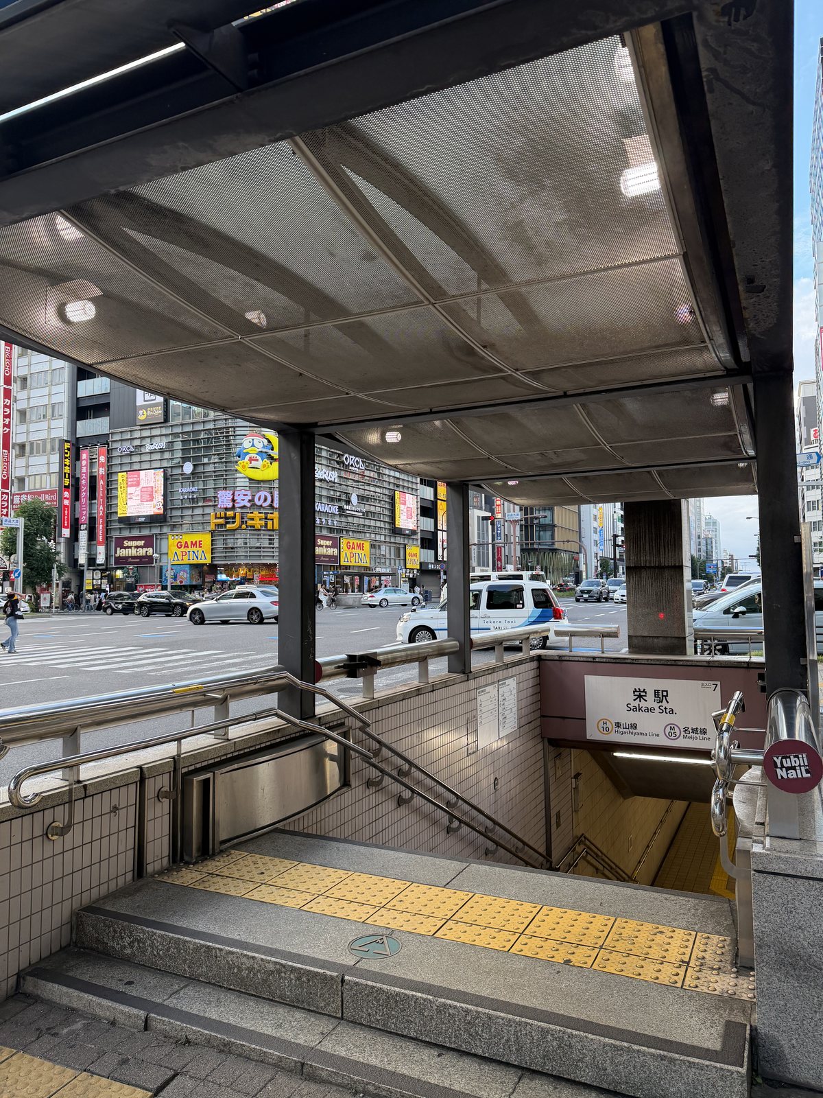 名古屋市営地下鉄 栄駅7番出口の地上側。下へ続く階段と栄の街並み