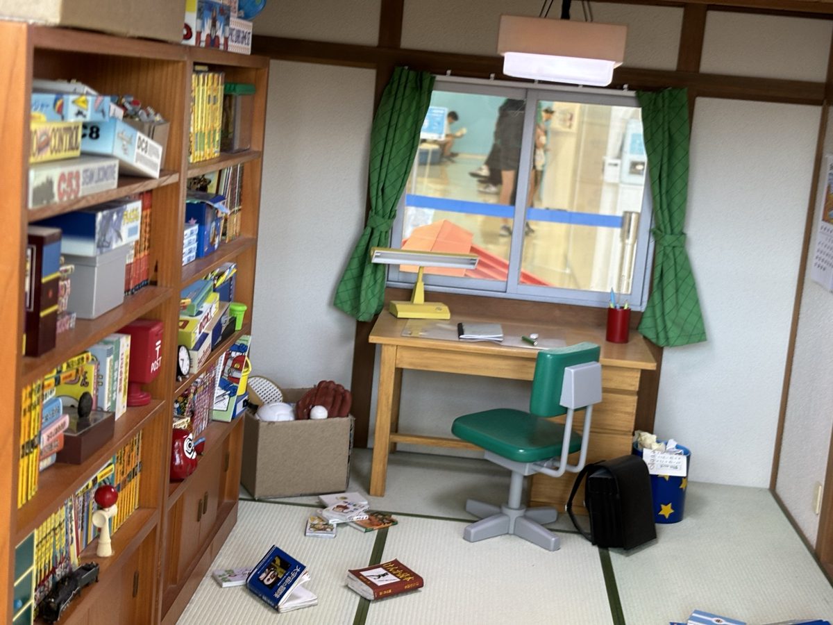 館内に再現されたのび太の部屋の模型|畳に勉強机と緑の椅子、本棚に鉄道模型のプラモデル箱が並ぶ