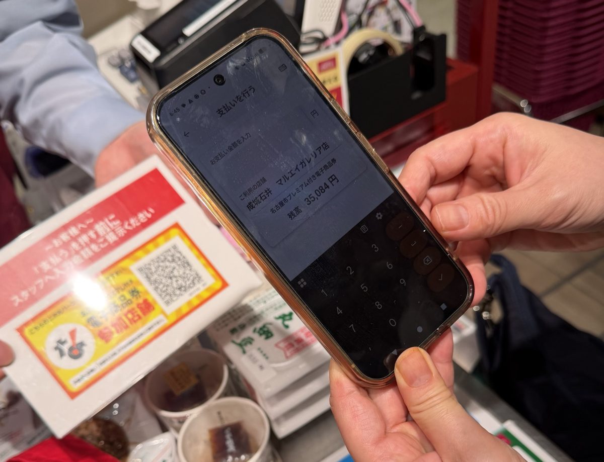 金シャチマネーの支払い画面の実物。成城石井マルエイガレリア店で1,577円を入力中、残高35,084円の表示