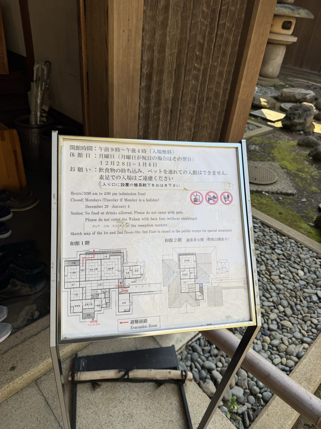 和館の入口に立つ案内板。開館時間9時から16時・入場無料・月曜休館の表示と、素足での入場はご遠慮ください・入り口に設置の簡易靴下をおはき下さいという注意、和館1階と2階の見取り図が示されている