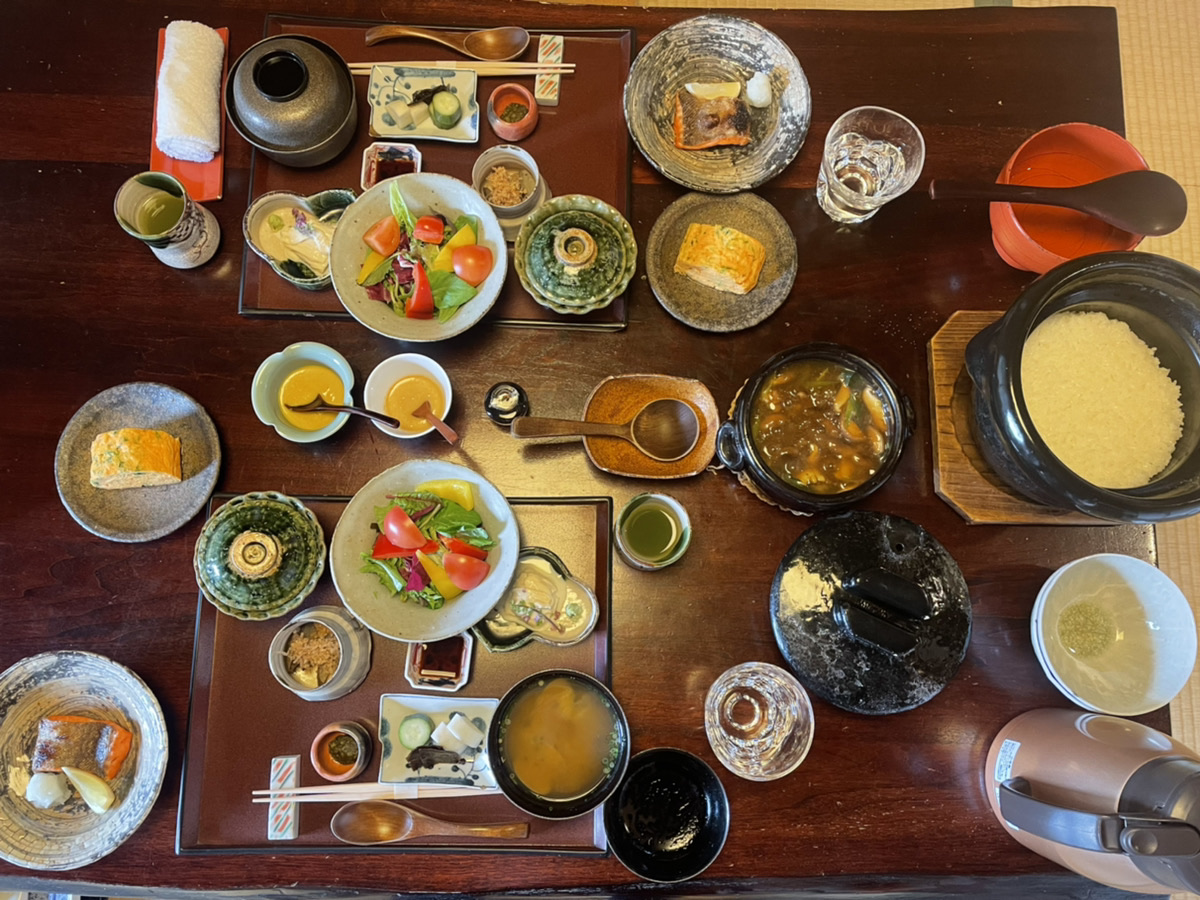 お宿うち山の朝食。土鍋で炊いたご飯、焼き魚、卵焼き、サラダ、味噌汁が2人分並ぶ