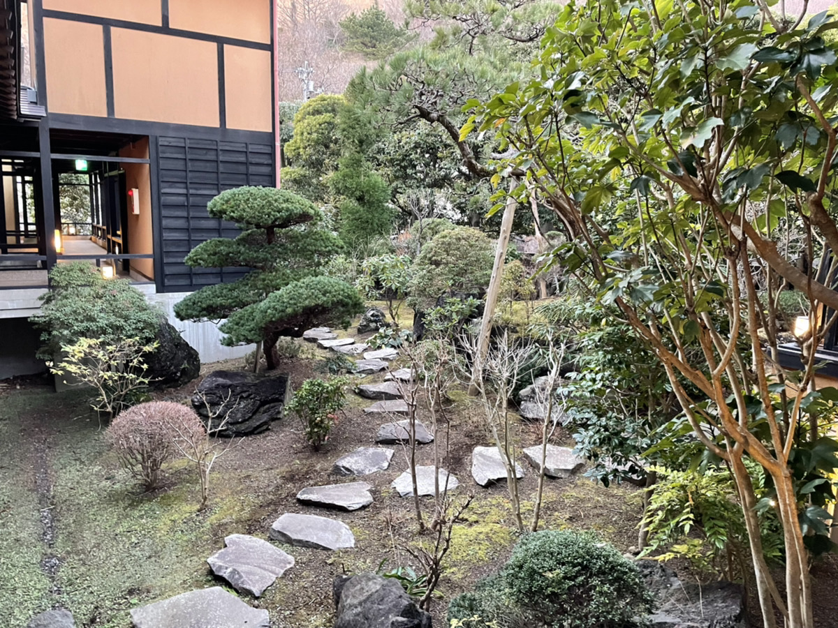 お宿うち山の中庭。飛び石の小道と手入れされた松、渡り廊下