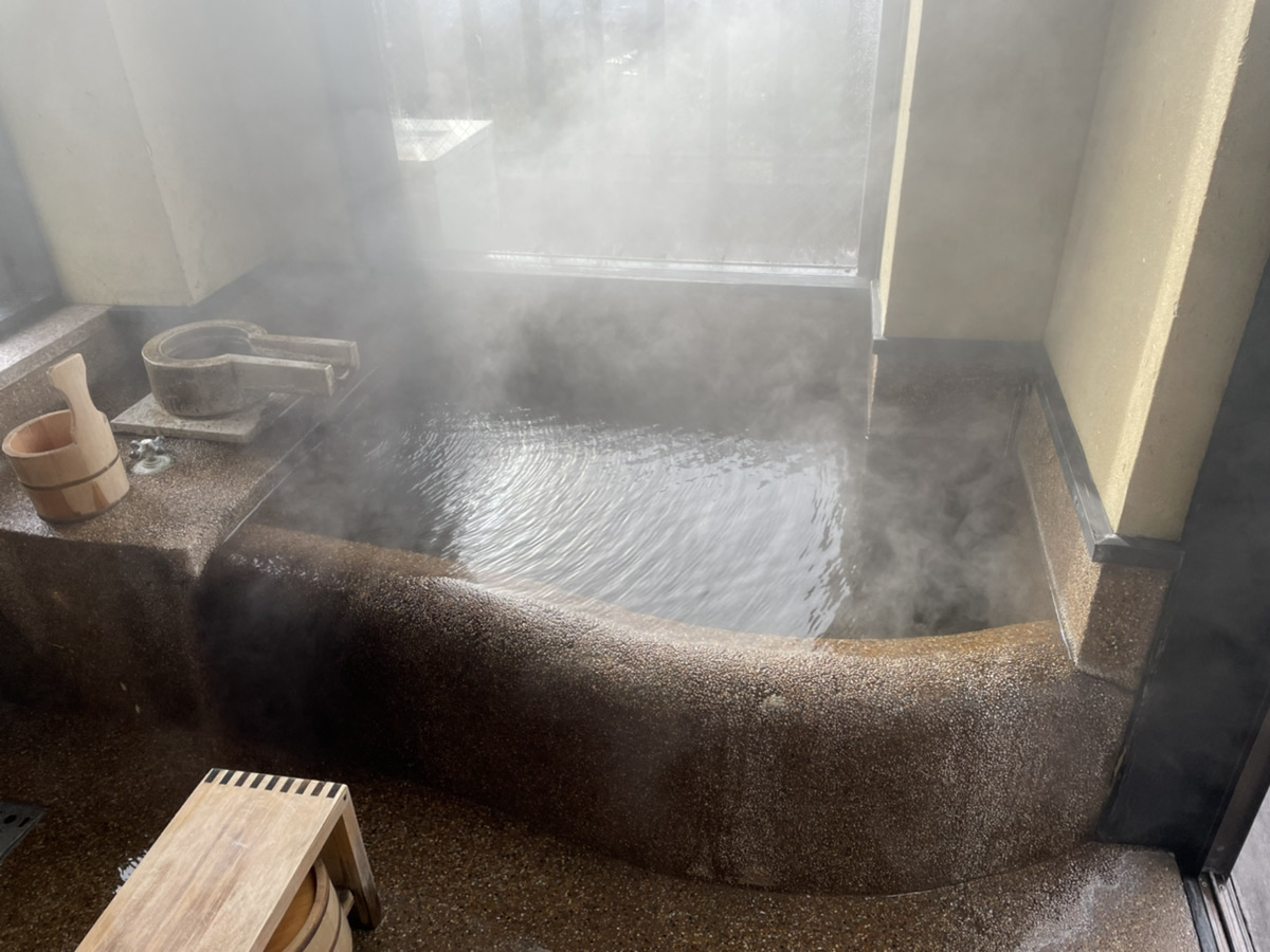 お宿うち山の内風呂。石造りの湯船から湯気が立ちのぼる