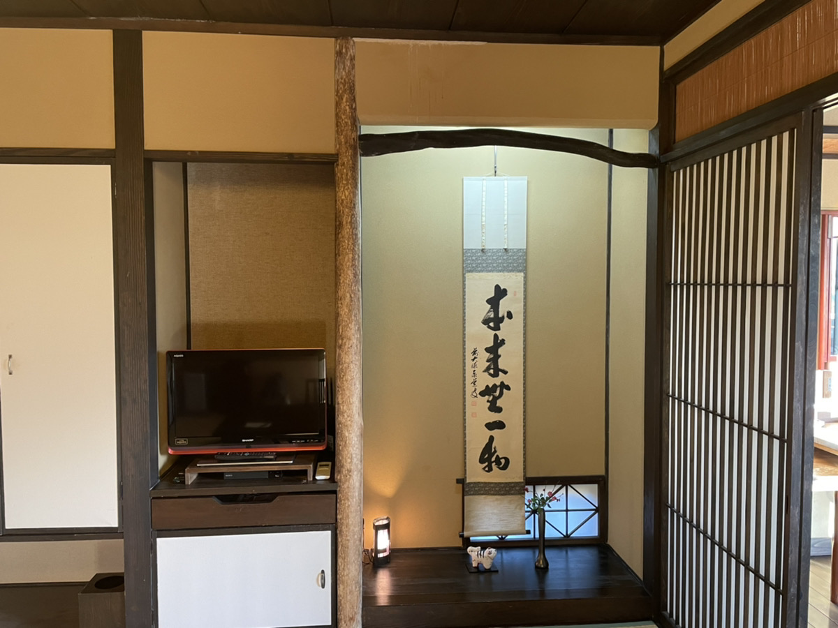 お宿うち山 雪タイプ1階の和室。床の間に掛け軸と一輪挿し、テレビと障子