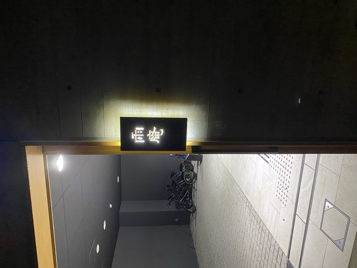 雨庵金沢の玄関。夜の黒壁に白く光る雨庵のサイン