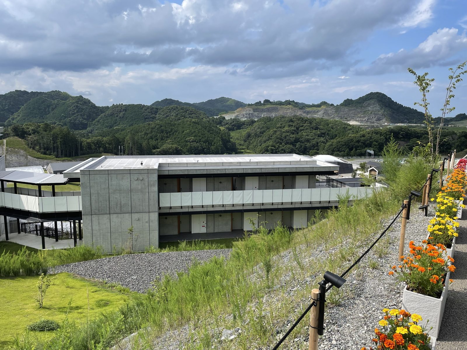 VISONの丘の上から見下ろした建物と、花の鉢が並ぶ小道(2022年7月)